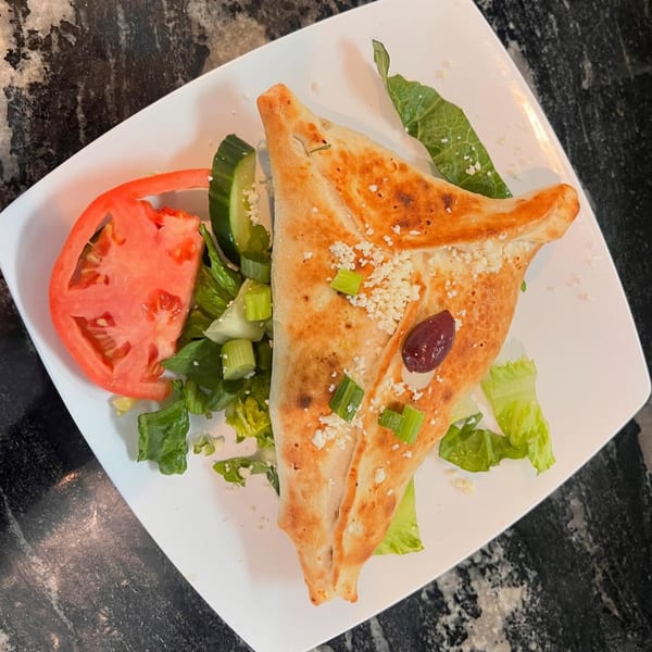 Dalia's Mediterranean calzone with feta, olives, and scallions, served with a side salad.