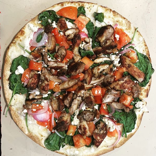 Dalia's Mediterranean pizza with chicken, spinach, tomatoes, red onion, and feta cheese.