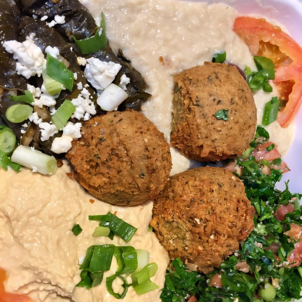 A Mediterranean platter with falafel, hummus, stuffed grape leaves, and tabbouleh salad.