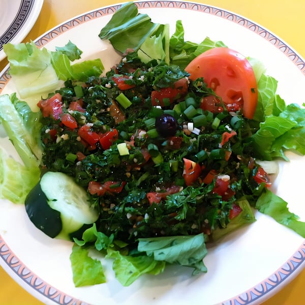 Dalia's tabbouleh salad with fresh parsley, tomatoes, green onions, and a cucumber slice.
