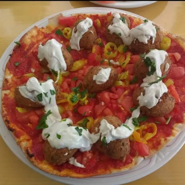 Dalia's Mediterranean pizza with falafel, diced tomatoes, yellow peppers, and a creamy white sauce.