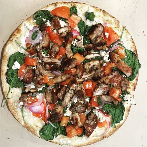 Dalia's Mediterranean pizza with chicken, spinach, tomatoes, red onion, and feta cheese.